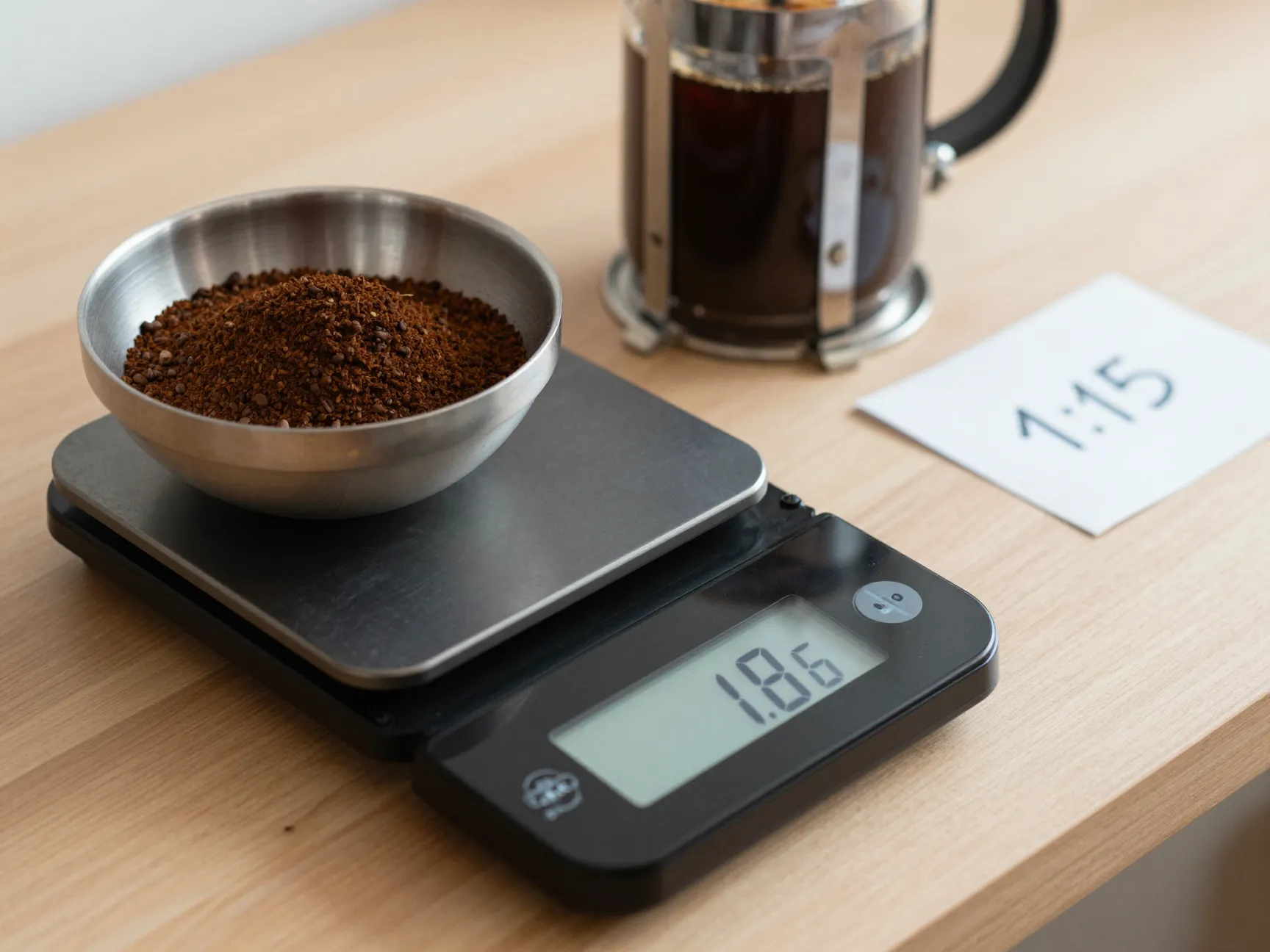 Digital kitchen scale weighing coffee grounds next to a french press