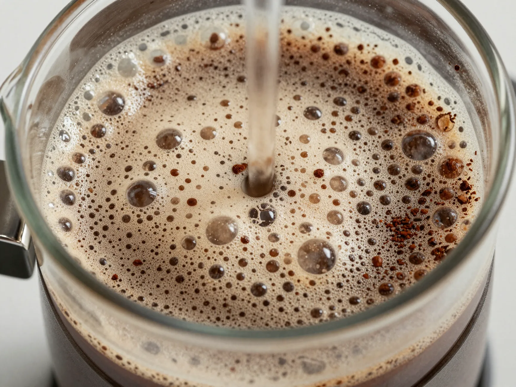 Fresh coffee grounds blooming with foam and bubbles in a french press