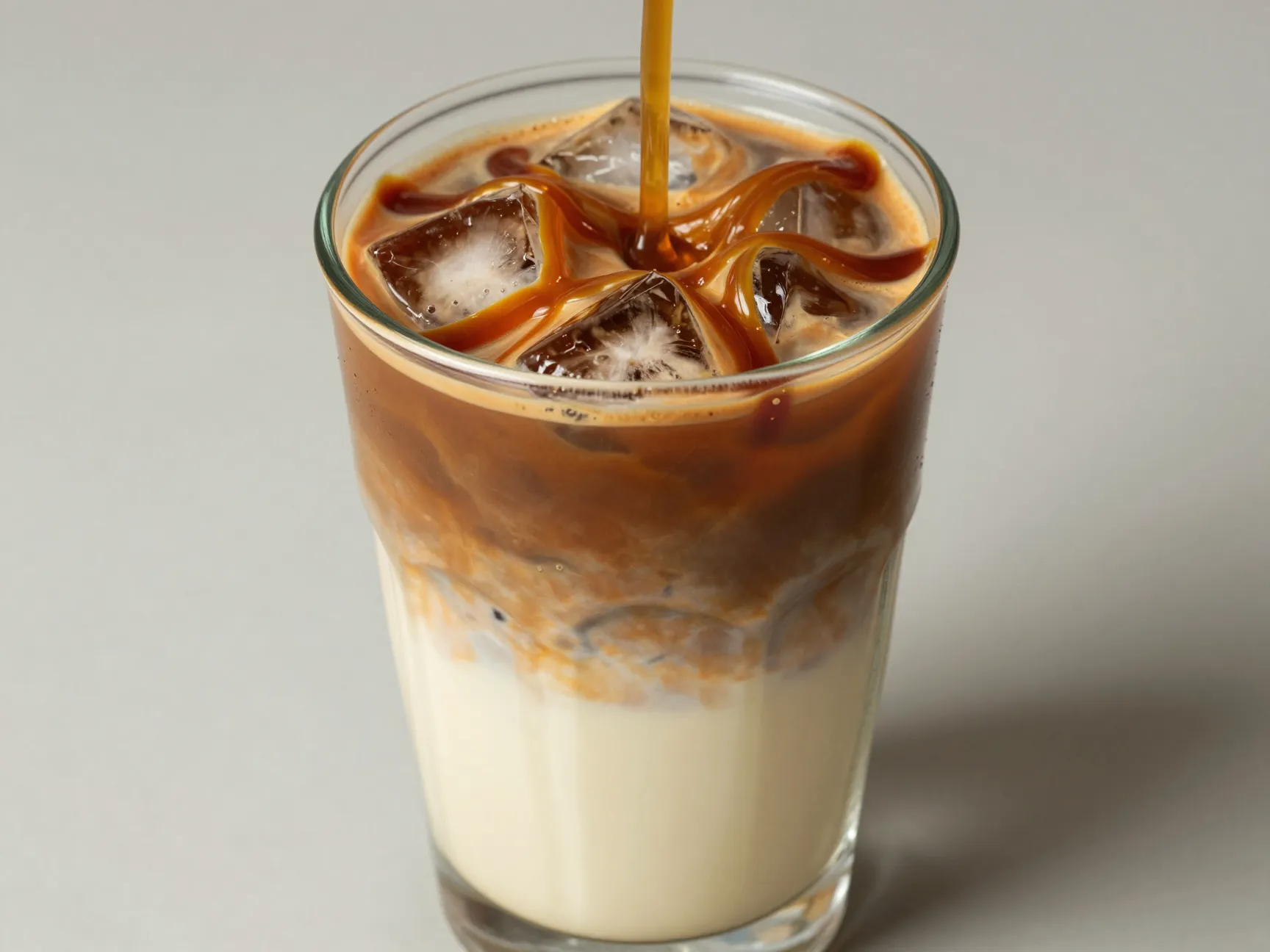 Iced tall glass caramel macchiato with dramatic layers over ice