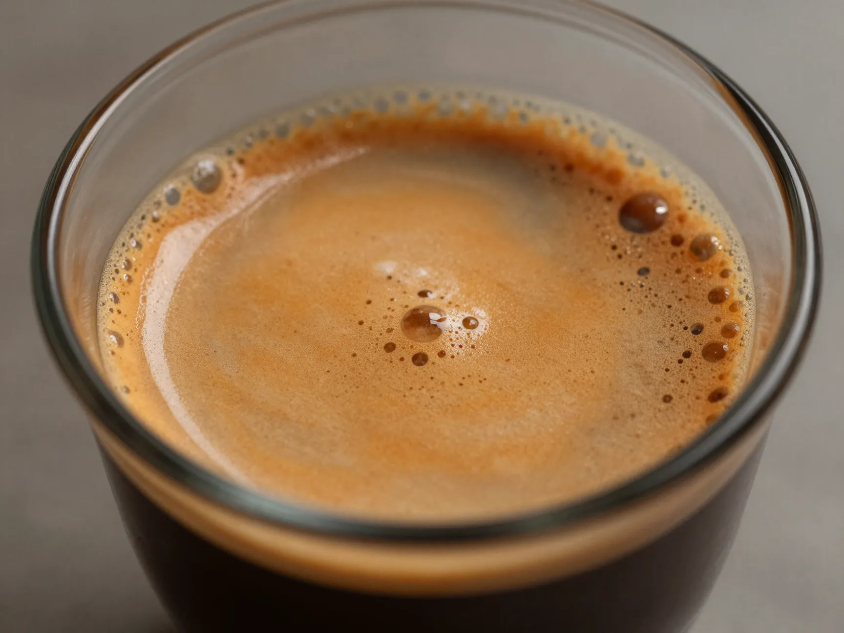 Freshly pulled espresso shot crema foaming in a small glass cup