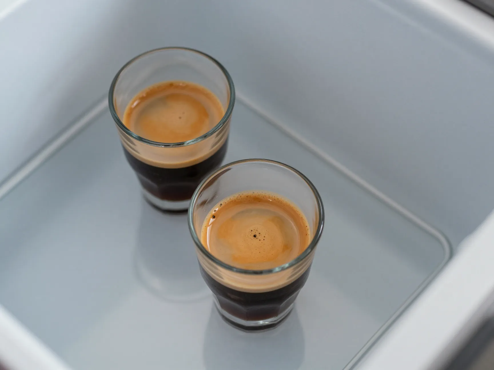 Espresso shot cooling in freezer next to small glass
