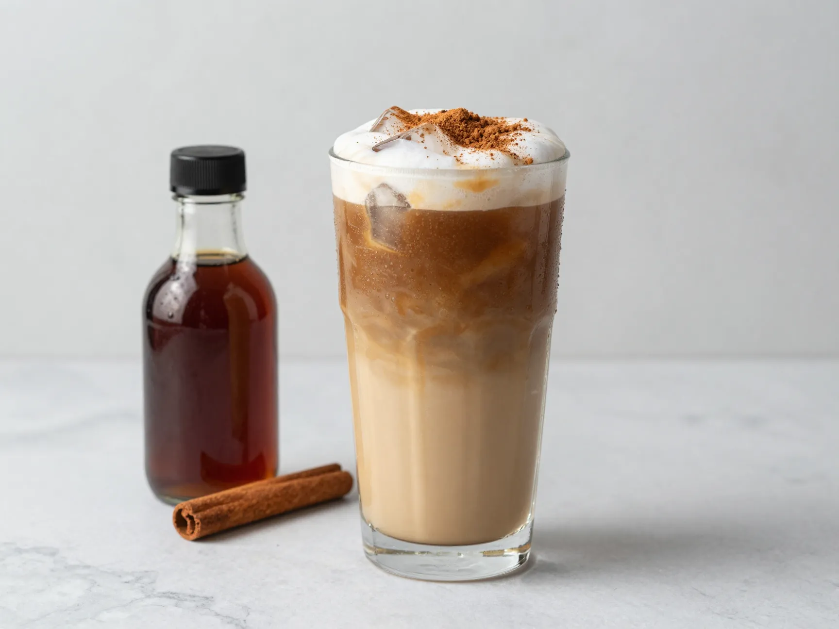 Iced brown sugar oat milk latte in tall glass with cinnamon and ice