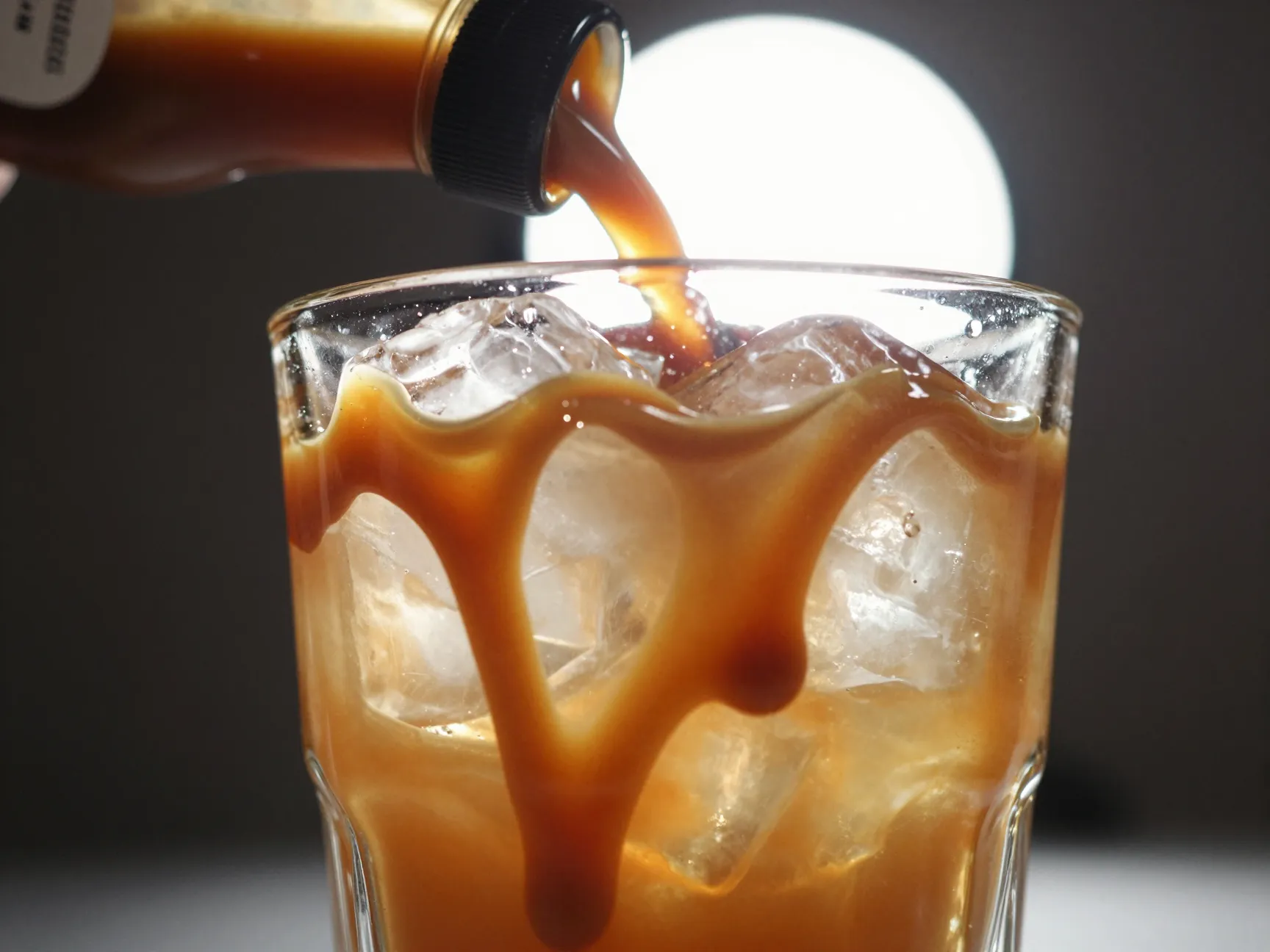 Caramel iced coffee with drizzle inside glass before ice