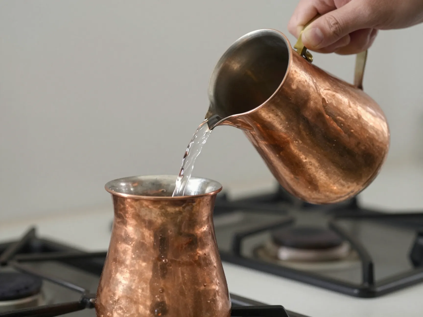 Pouring cold water from demitasse cup into copper cezve