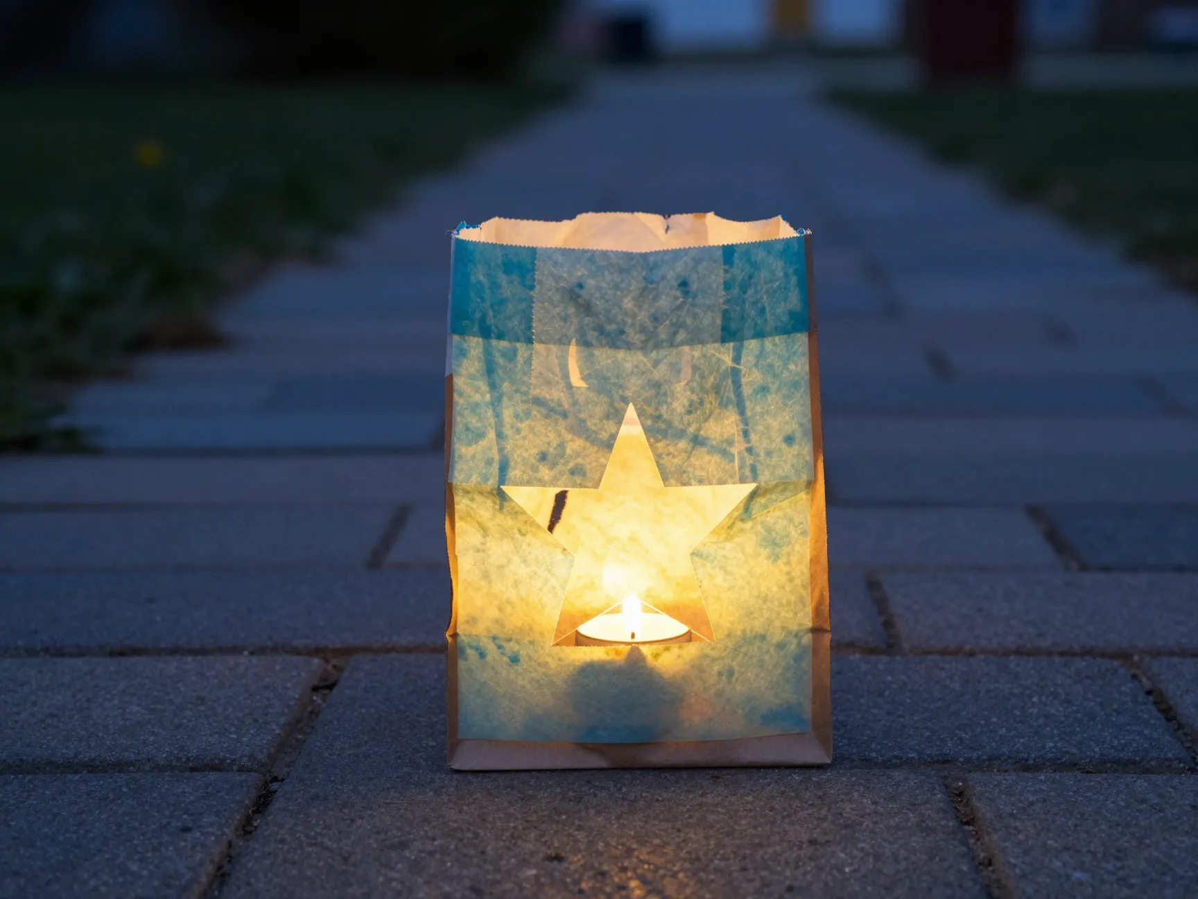Dyed coffee filter luminaria bag with cut out star shape glowing on walkway