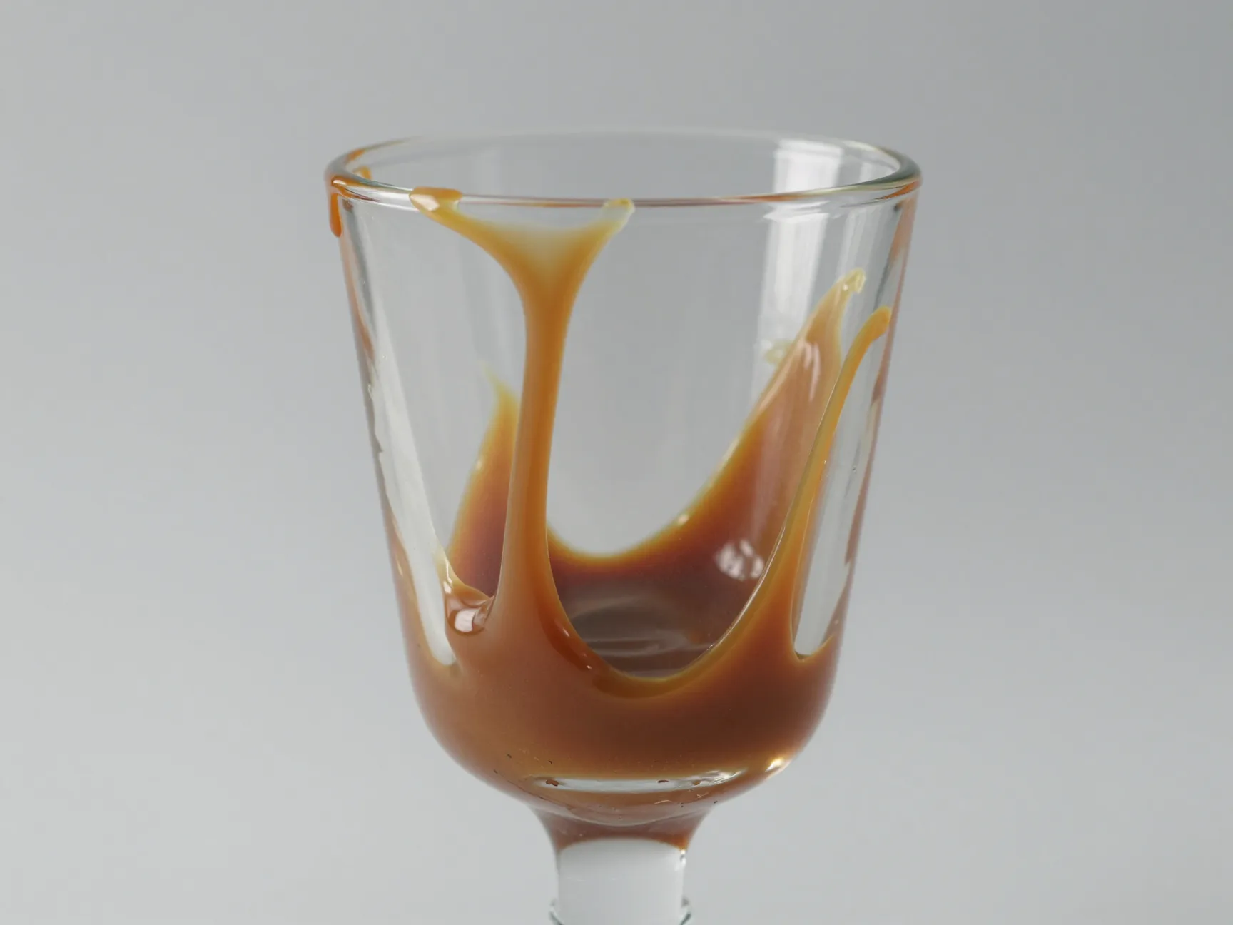 Caramel sauce lined inside clear glass cup before beverage assembly