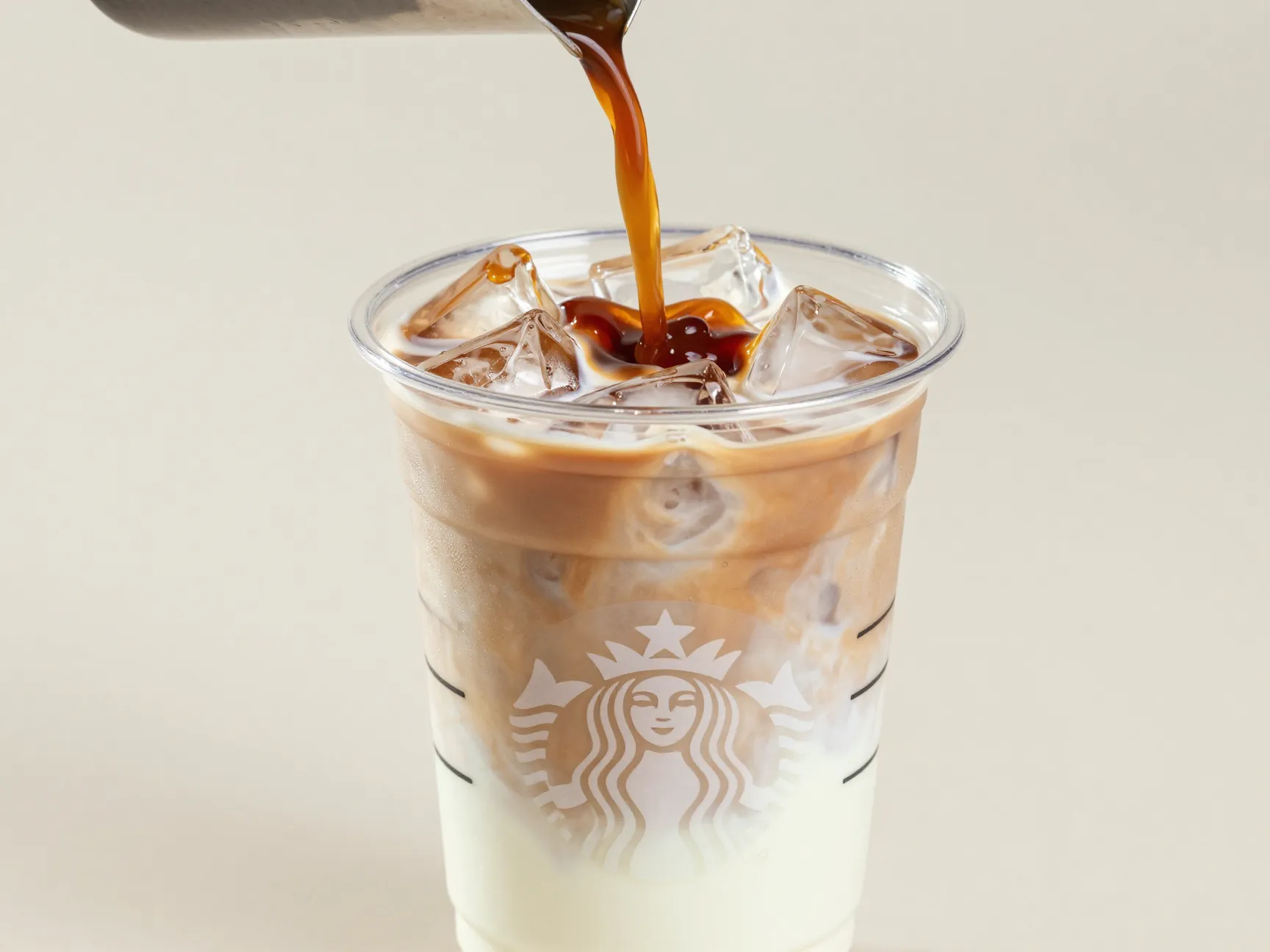Iced caramel macchiato in clear plastic cup with visible sinking espresso
