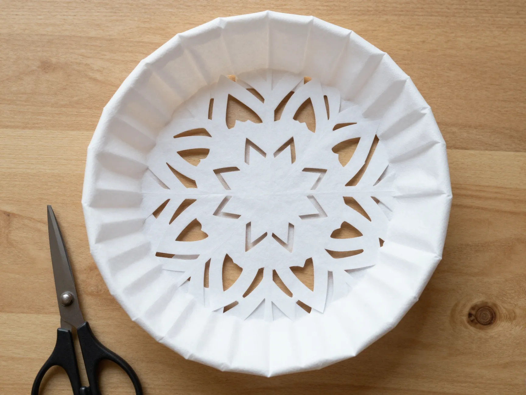 Coffee filter folded and cut symmetrical intricate snowflake craft