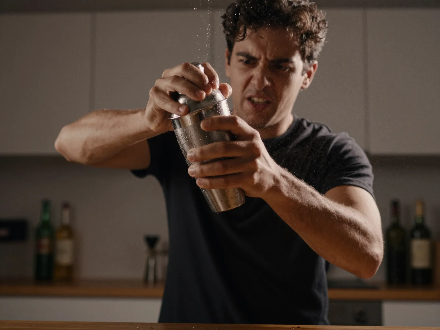 Bartender vigorously shaking cocktail shaker with both hands