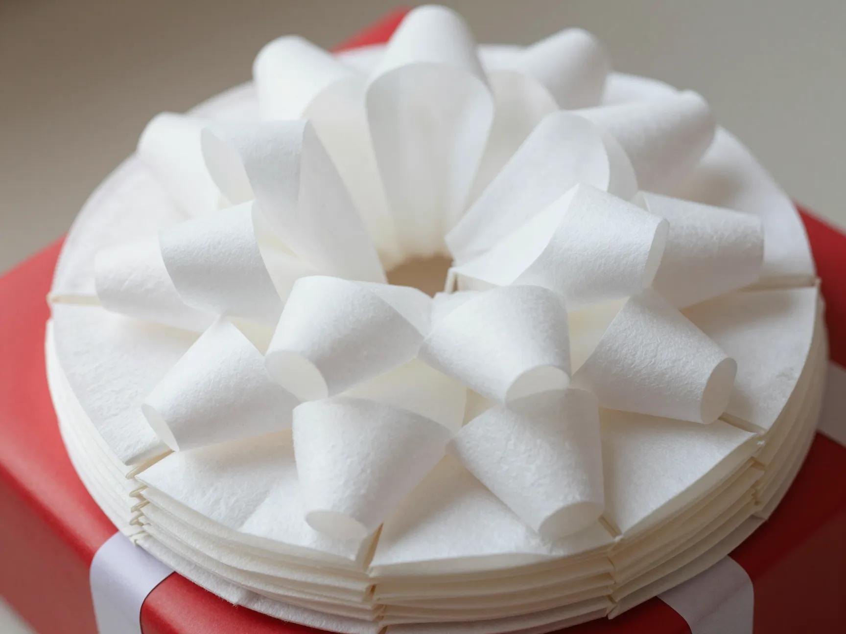 Fluffed accordion folded stack of white coffee filter gift bow