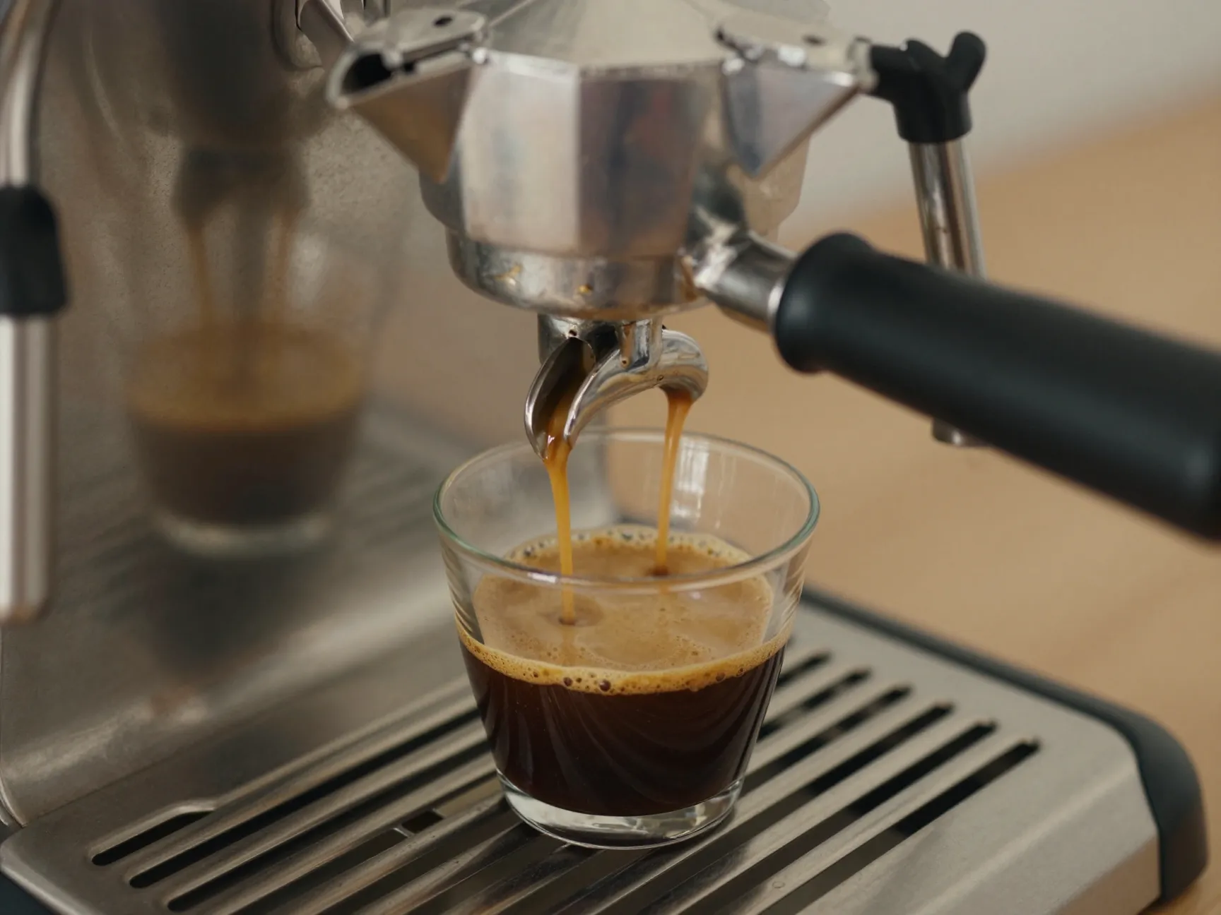 Coffee maker pouring fresh espresso into small cup