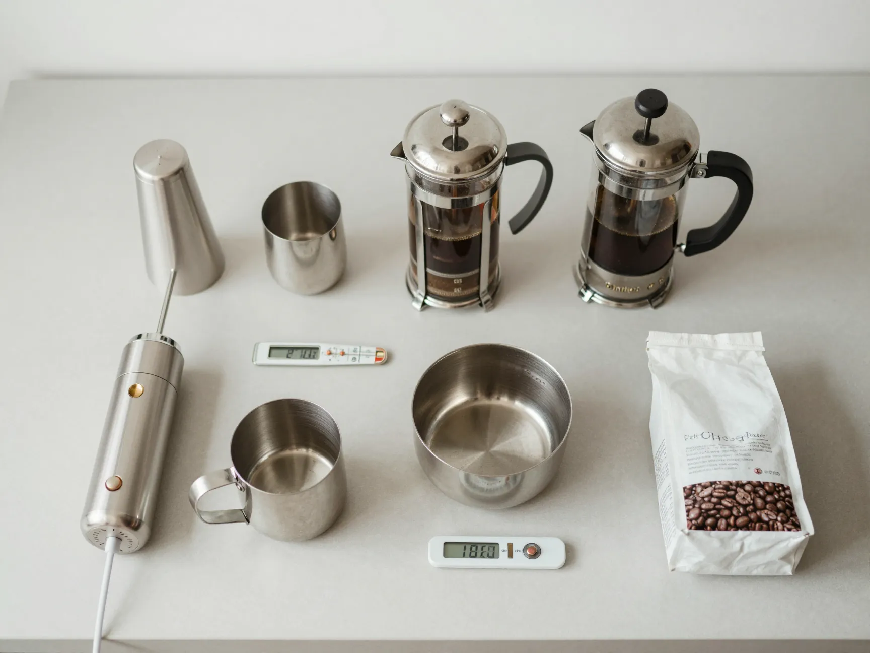 Handheld milk frother and french press on simple kitchen counter