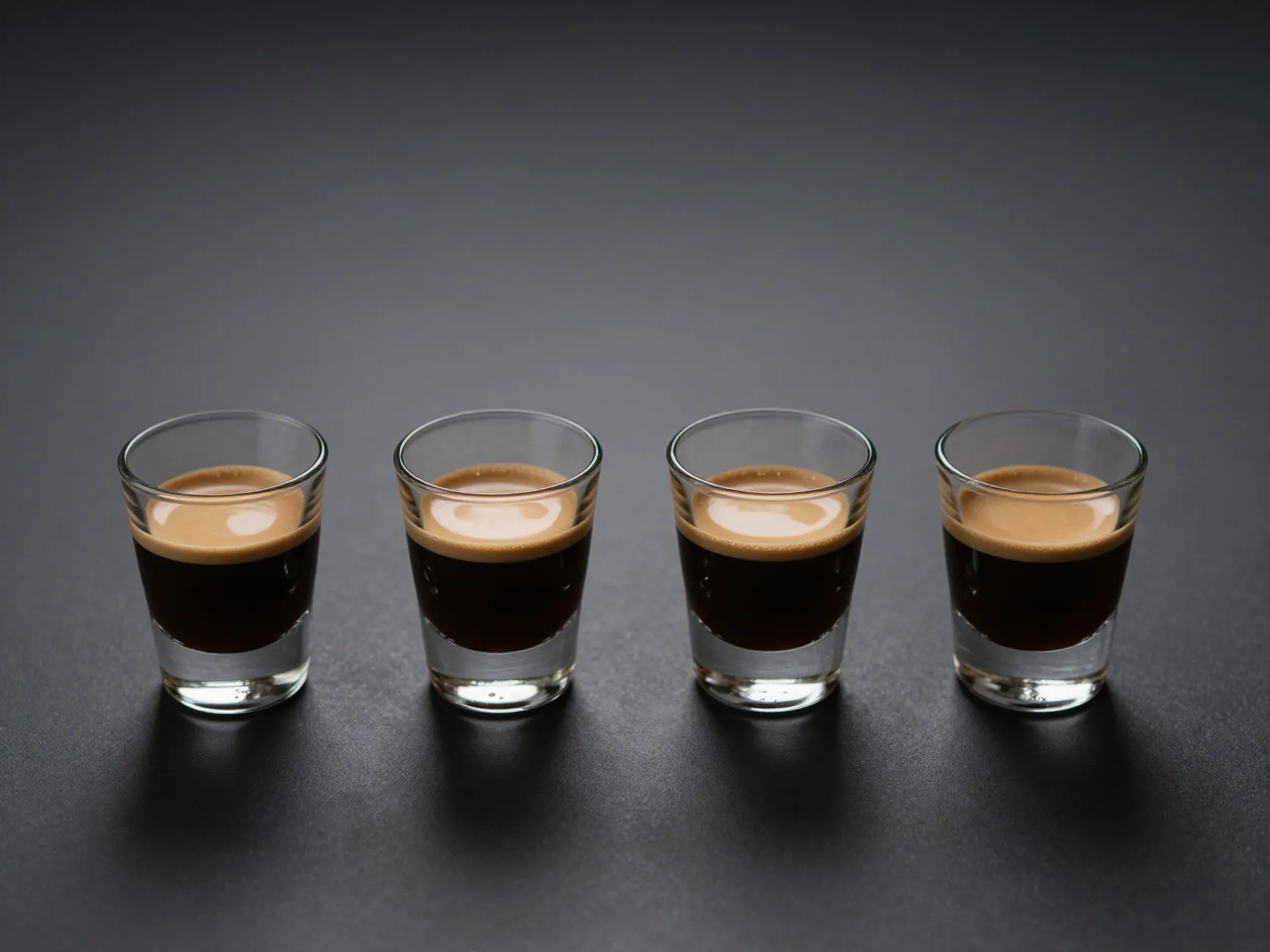 Four espresso shot glasses lined up in row