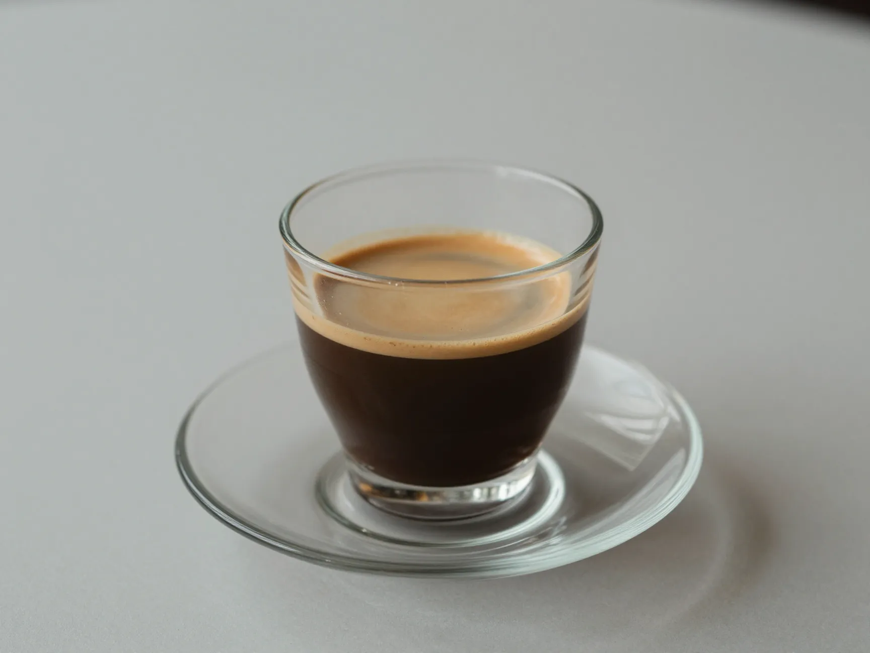 Clear glass of light brown caffe lungo coffee for sipping