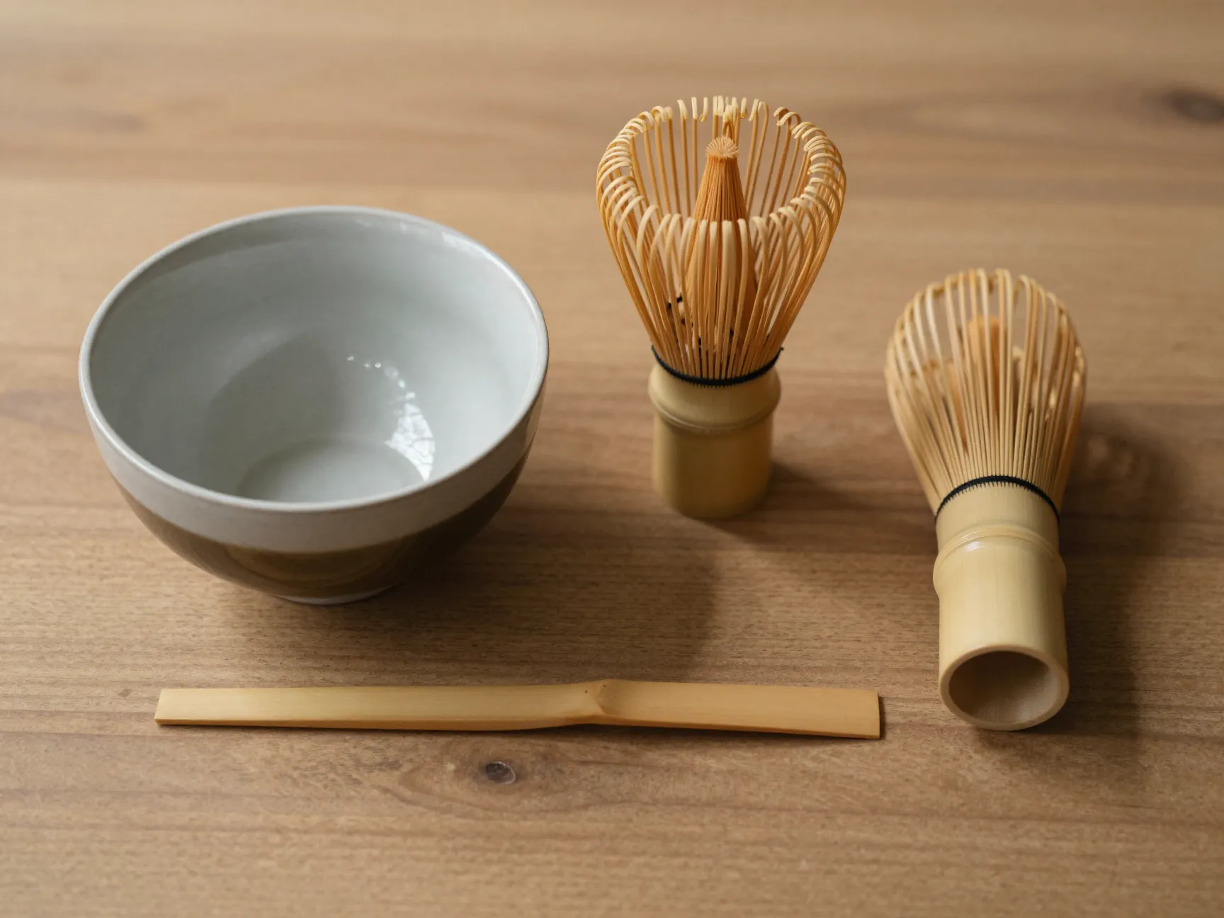 Traditional matcha tools chawan chasen and chashaku arranged on wooden surface