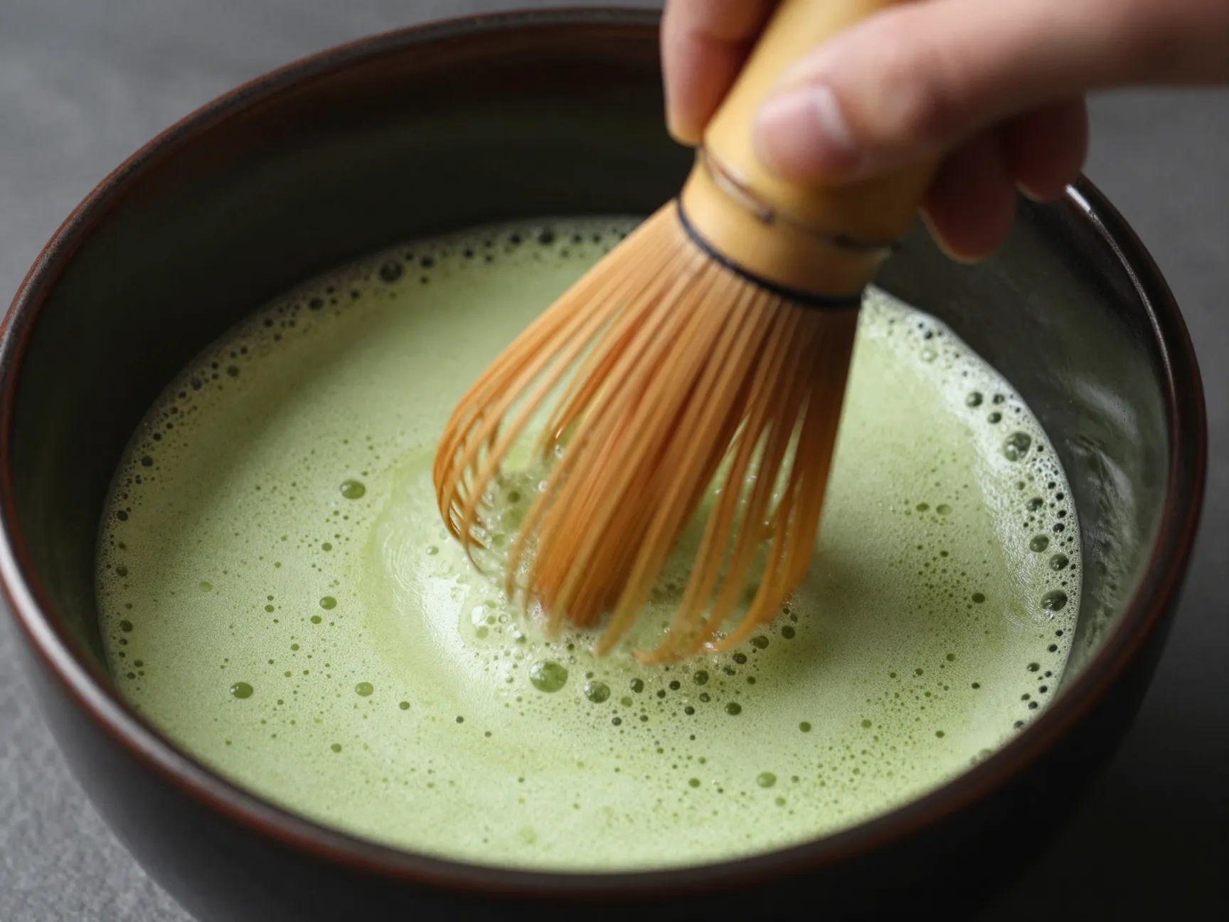 Whisking matcha with bamboo chasen in vigorous w shaped motion