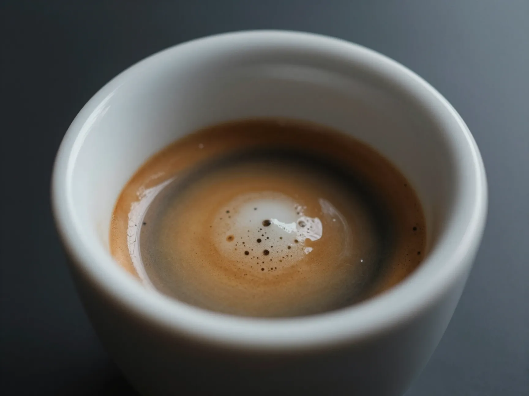 Double shot espresso macaroni with foam dollop in demitasse cup