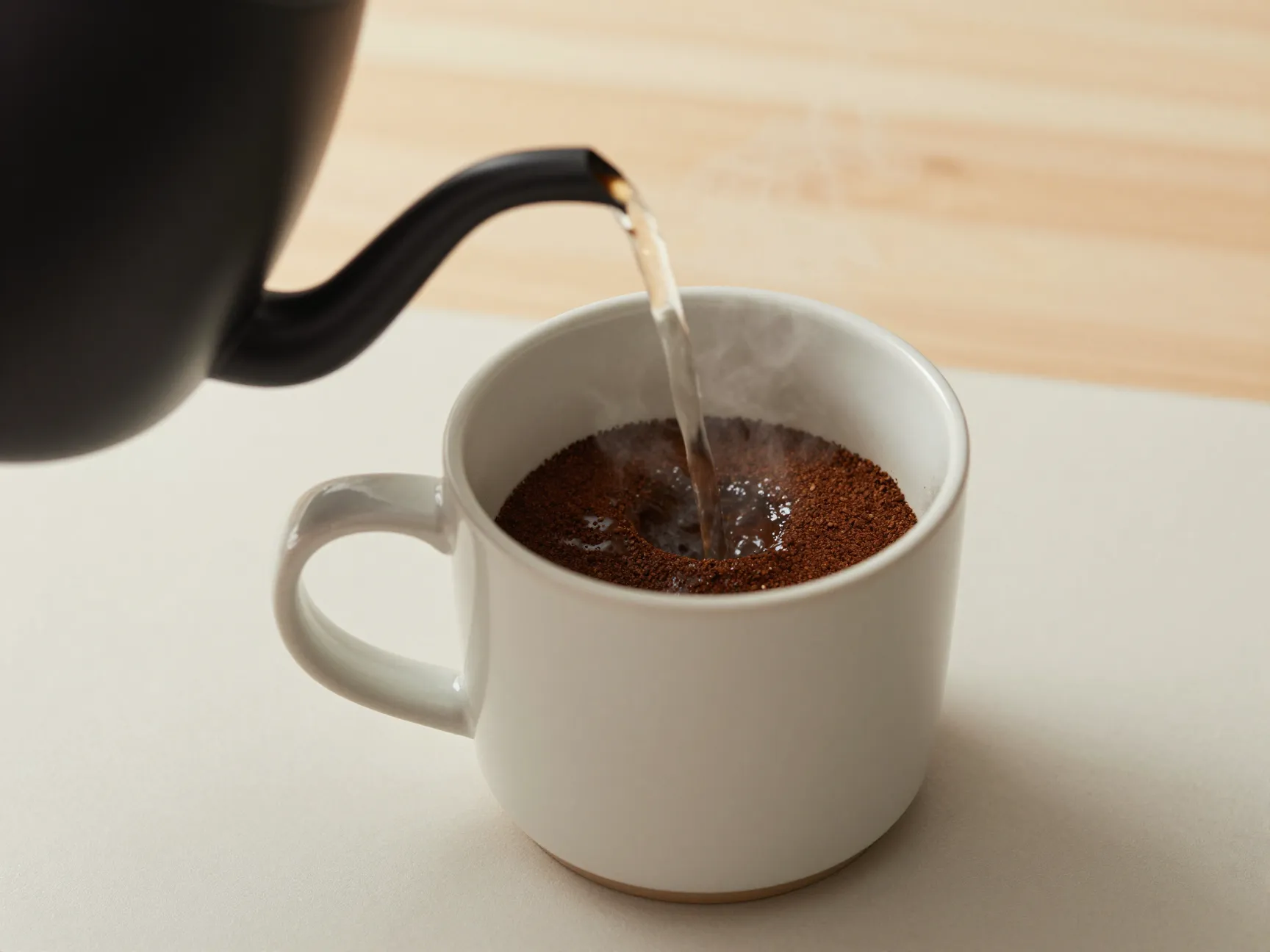 Mug with coffee grounds and hot water in simple room