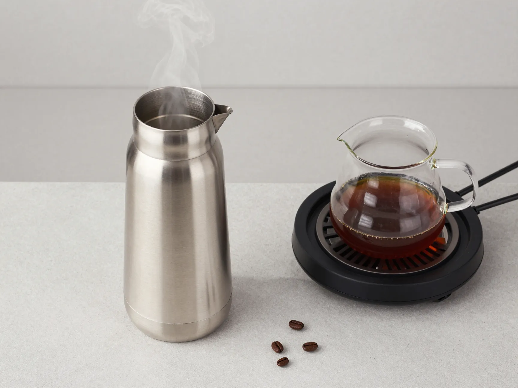Full thermal carafe of hot coffee on counter next to empty hot plate