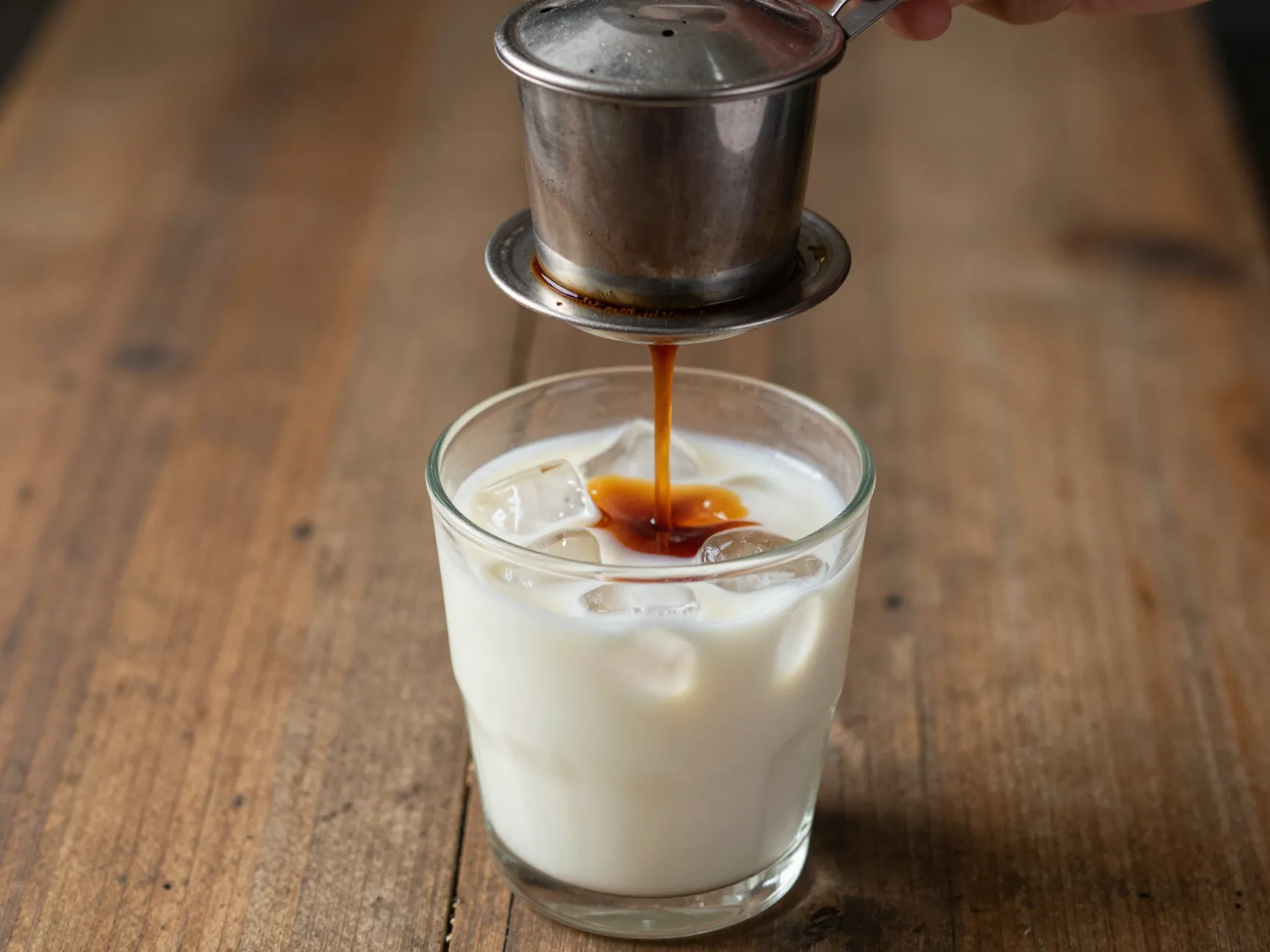 Vietnamese iced coffee with phin filter over condensed milk