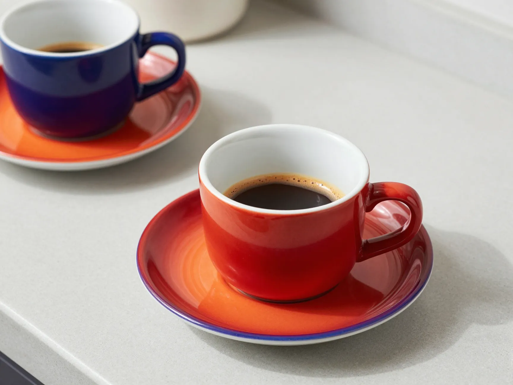 A vibrant enamel coated stoneware espresso cup on a kitchen counter