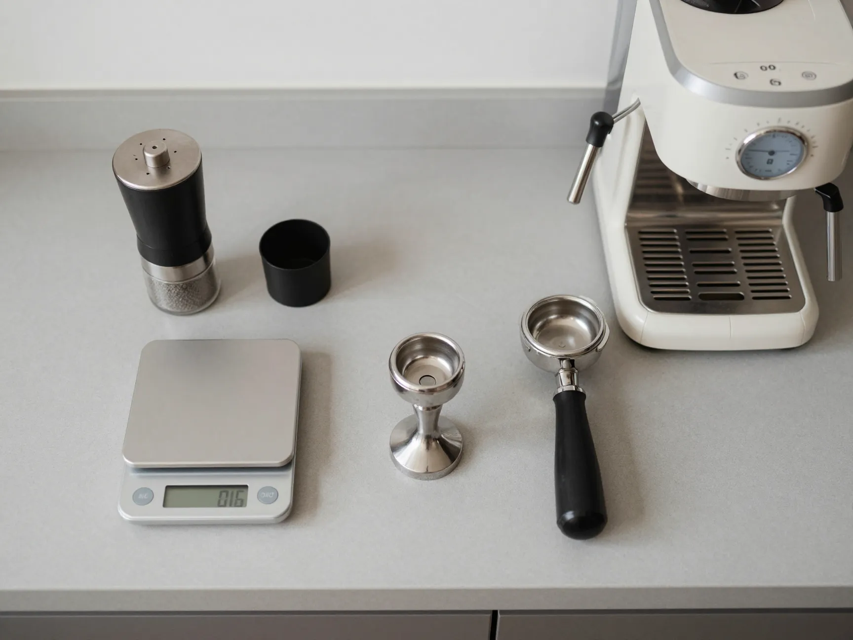 Essential espresso tools burr grinder scale tamper and machine on counter