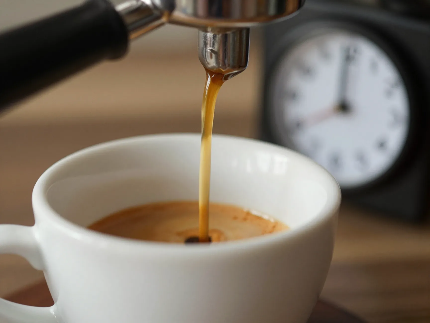 Honey golden espresso shot flowing into a preheated ceramic cup