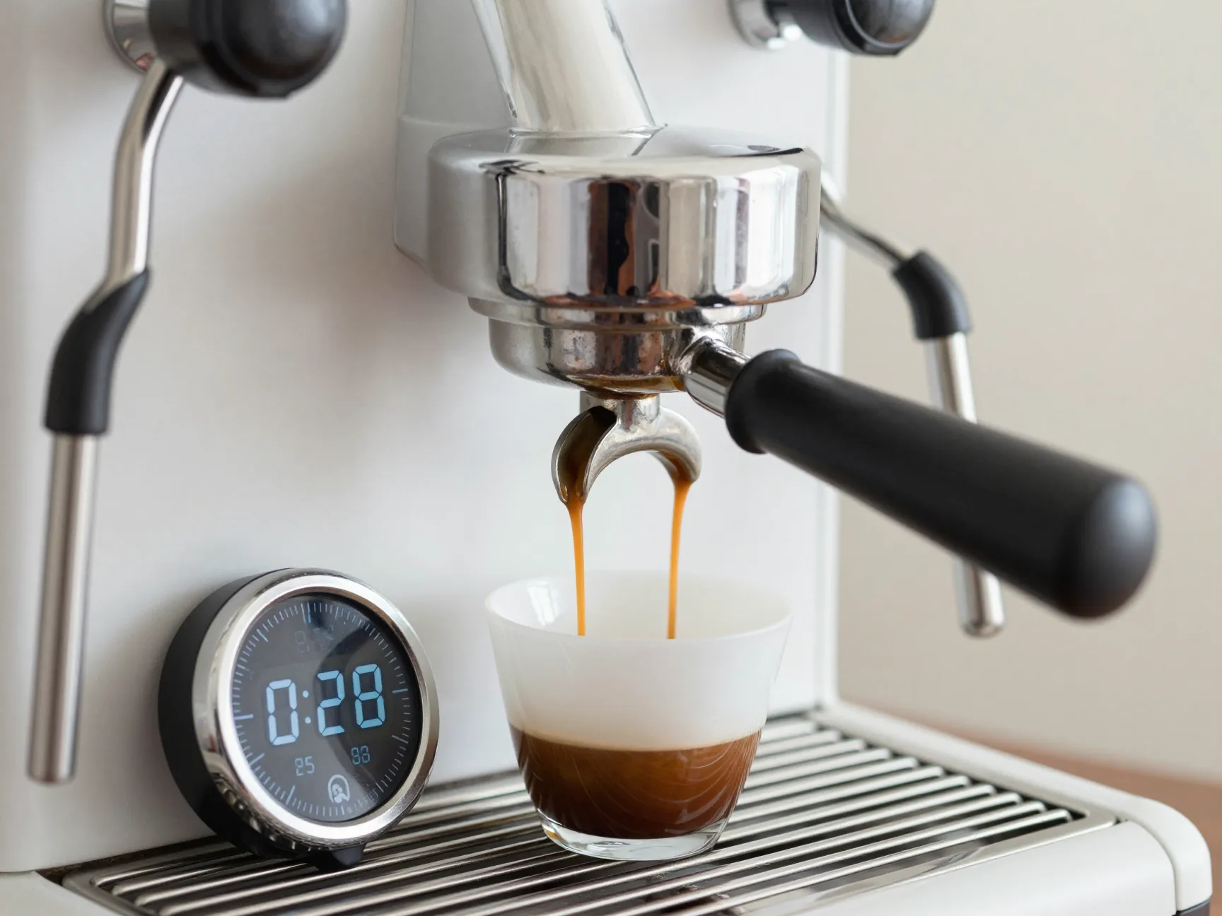 A digital timer next to an espresso machine during extraction