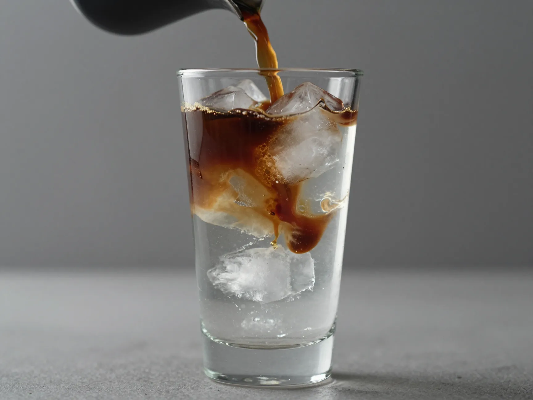 Ice cubes cold water and espresso layered in a clear glass