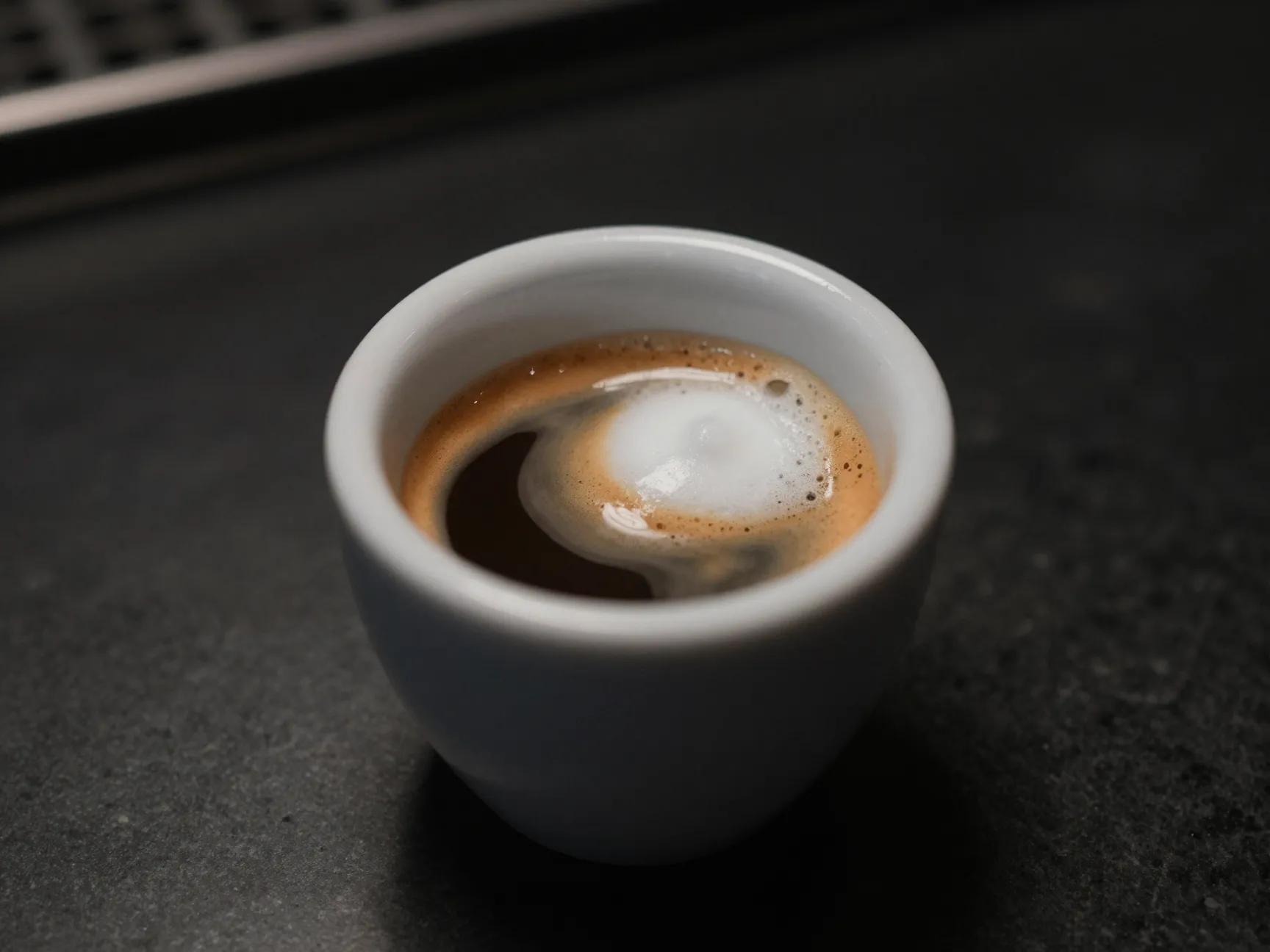 Espresso macchiato stained with dollop of foam in tiny cup