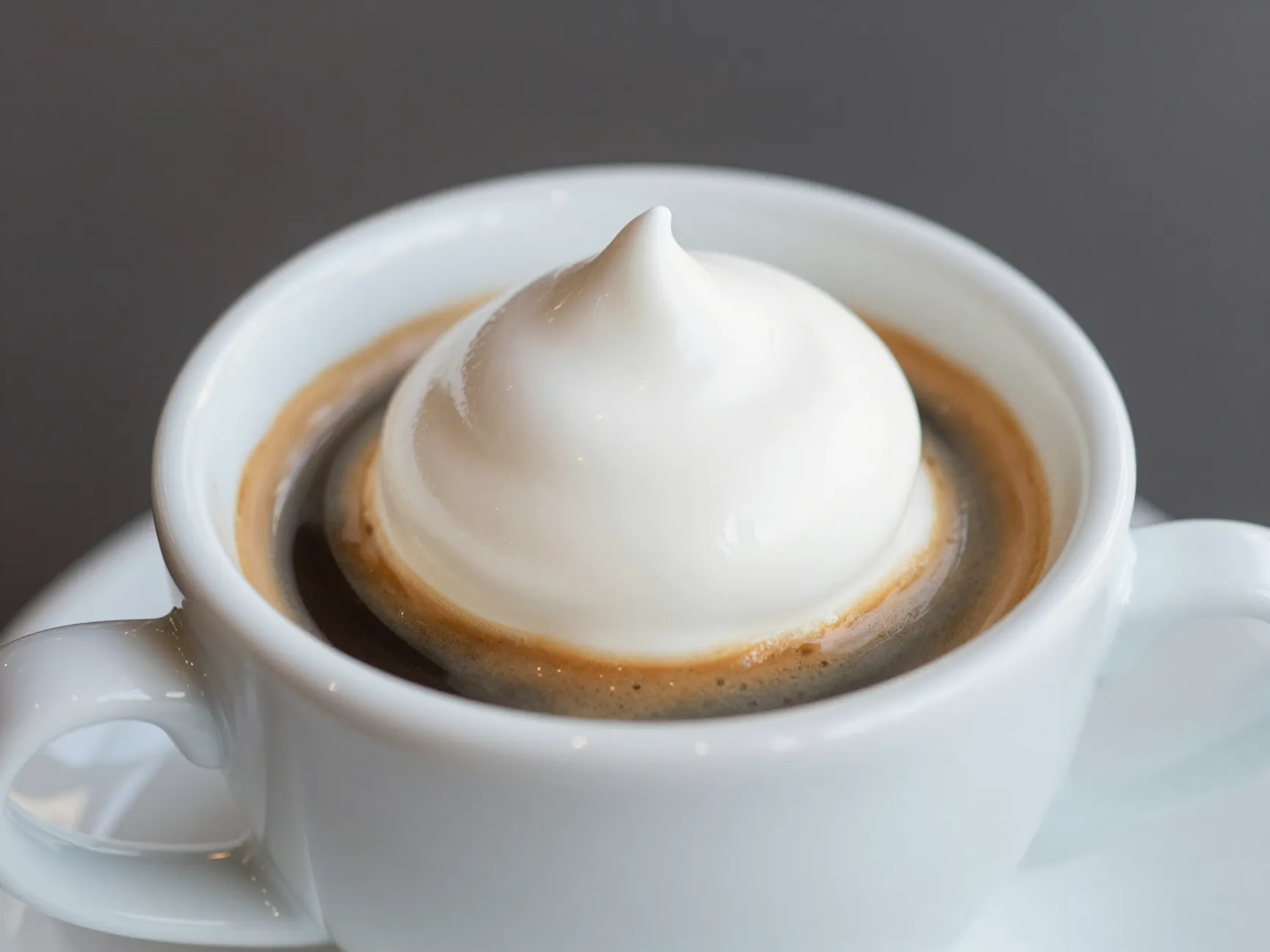 Demitasse cup espresso shot topped with white whipped cream dollop