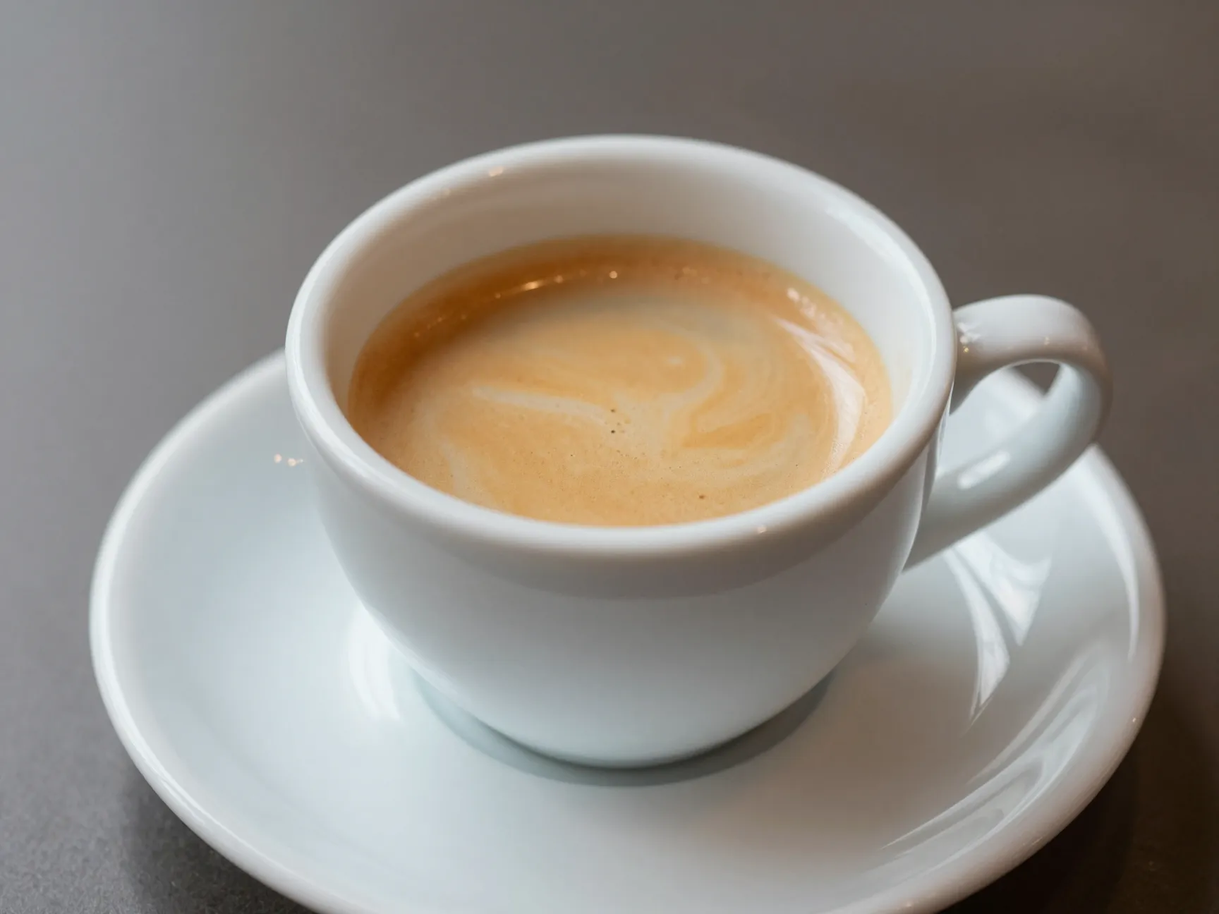 Small white ceramic cup with equal parts espresso and steamed milk