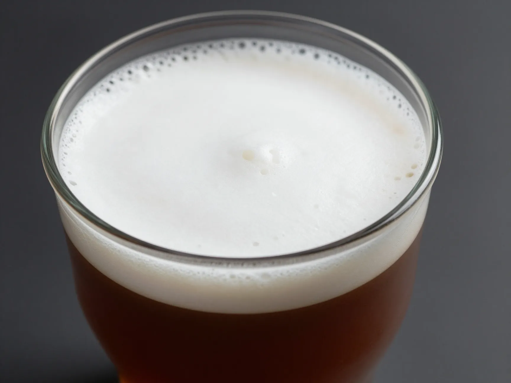 Higher coffee to milk ratio of a flat white in a clear glass cup