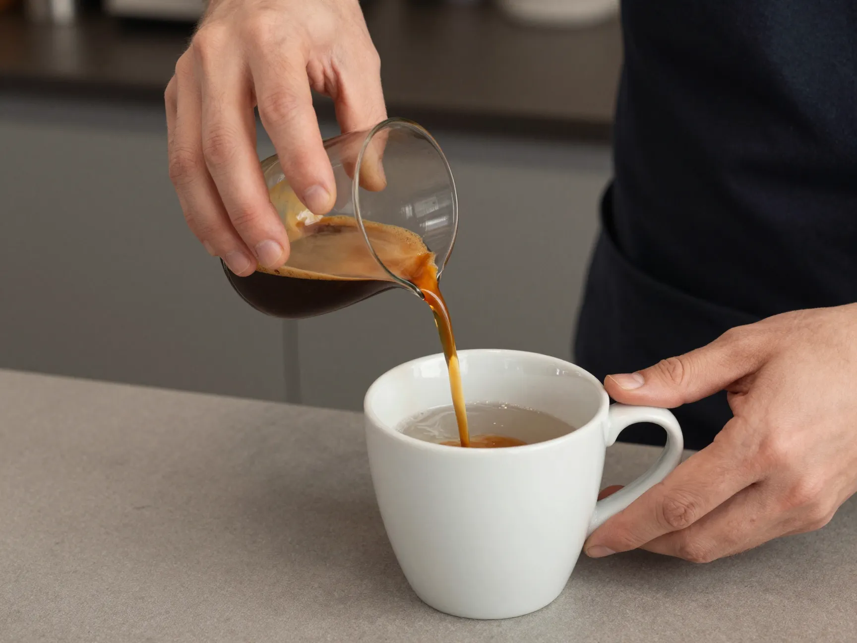 Barista gently pouring espresso into a mug of hot water technique