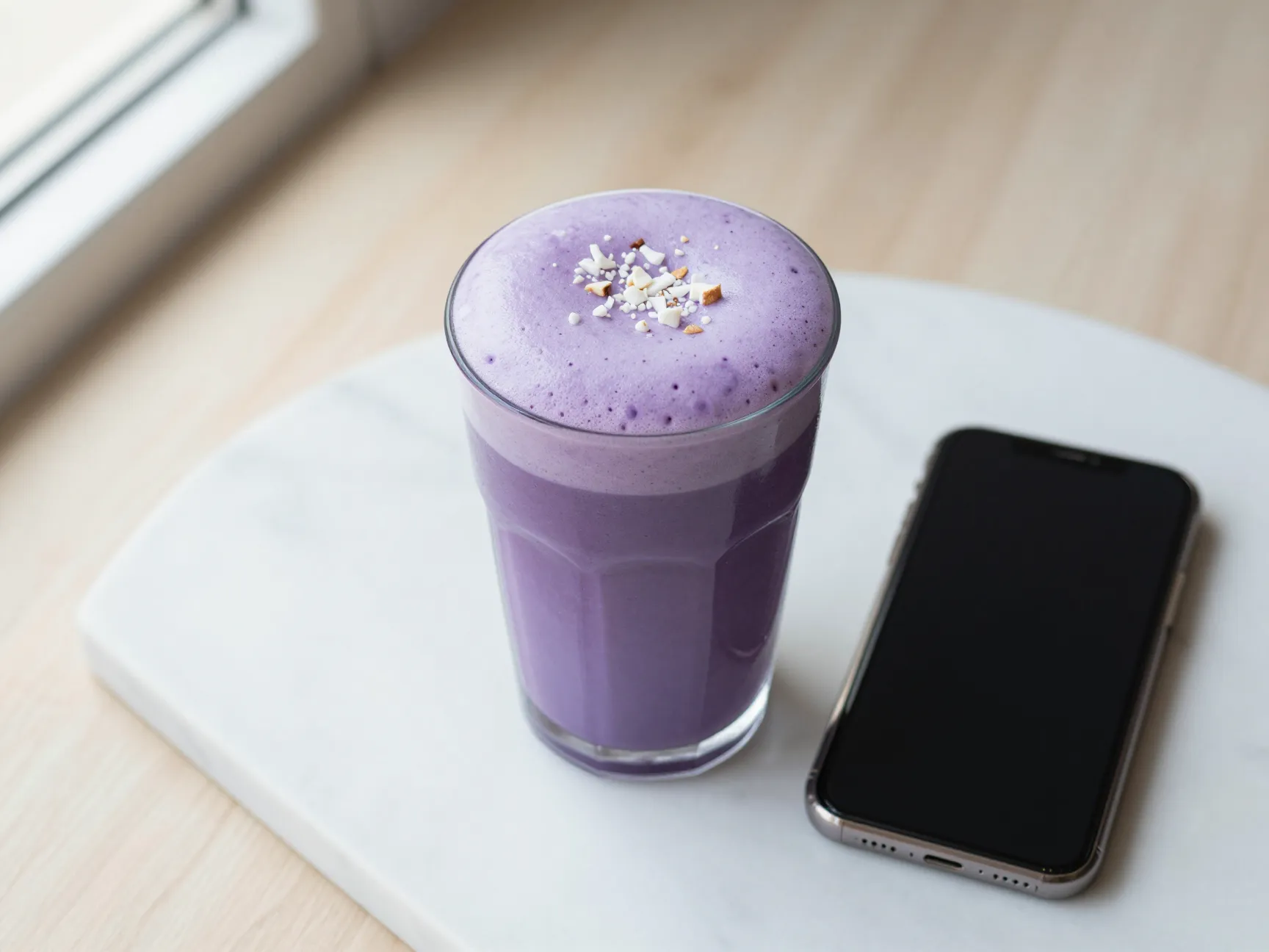 Instagram worthy iced ube macchiato on marble surface with phone