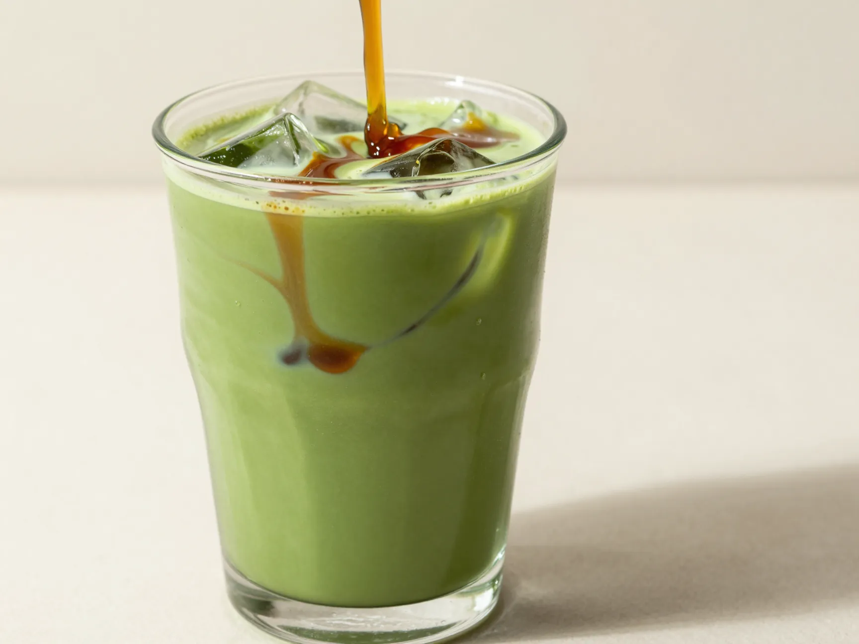 Iced matcha latte with chai syrup creating a swirled effect