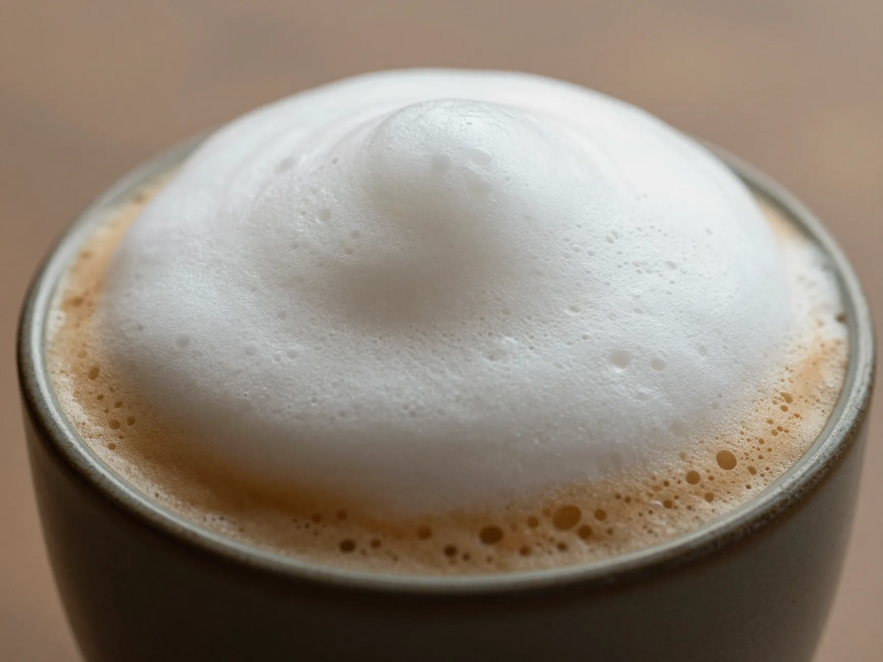 Thick airy foam dome atop a small concentrated cappuccino drink