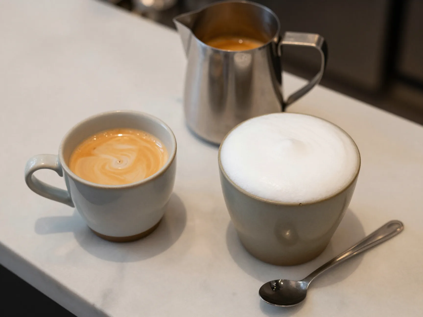 Flat white and latte side by side on marble coffee counter