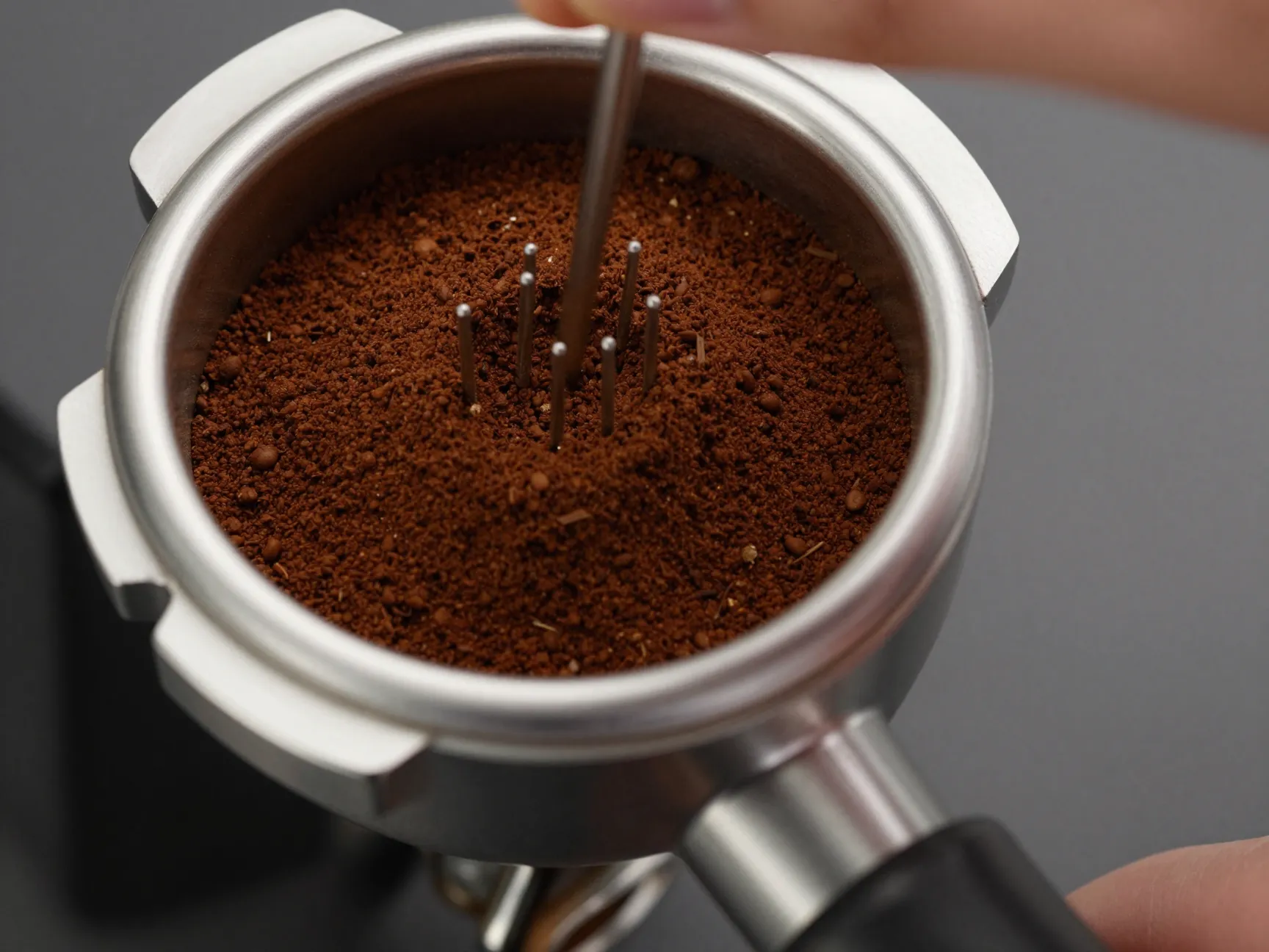 Metal wdt tool distributing ground coffee in a portafilter basket to prevent clumping